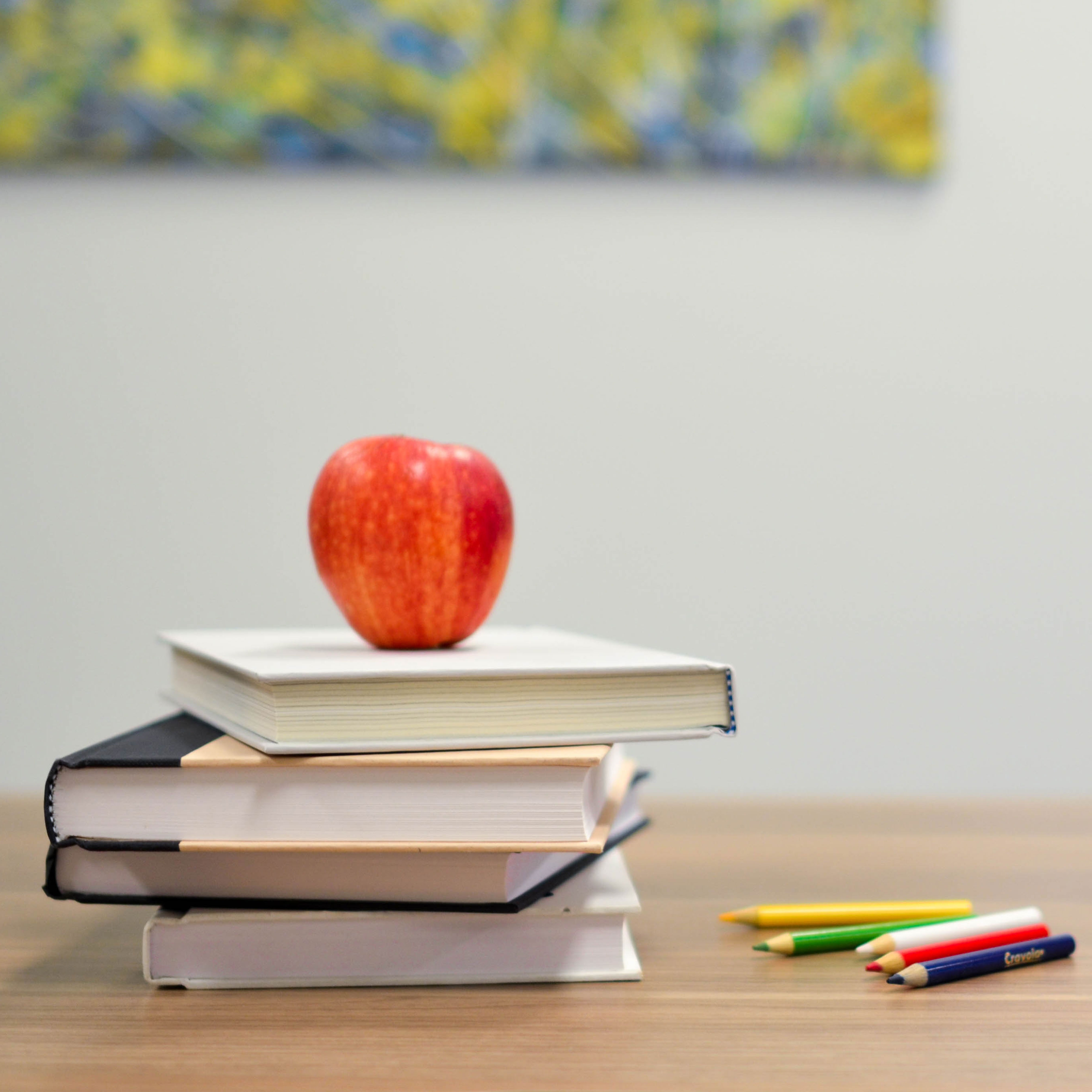 Desk with books, pencils, blocks and a apple on it